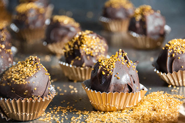 Chocolate Covered Cookie Dough Bites wrapped in gold wrappers with gold sprinkles