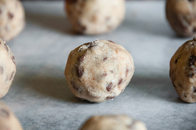 Cookie dough rolled into equal sized balls on wax paper
