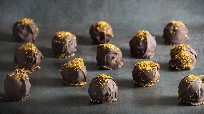 Chocolate candies with gold sprinkles on a gray counter
