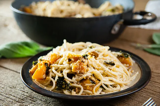 Spaghetti, kale, mushrooms, squash, garlic, sage, and walnuts on wood