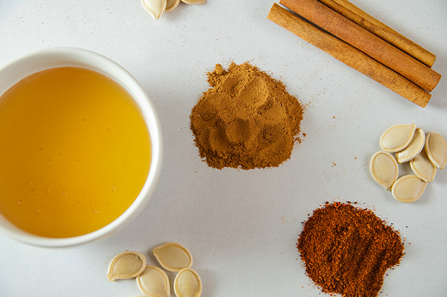 Honey, cinnamon, and chili powder with pumpkin seeds on white