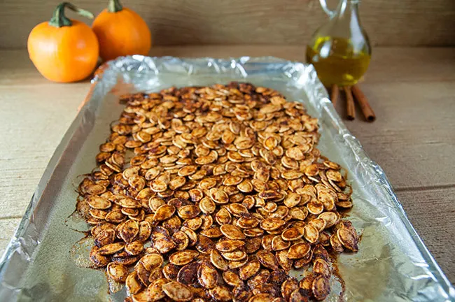 Spiced pumpkin seeds on a cookie sheet lined with aluminum foil