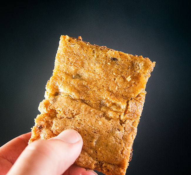 Triple Chocolate Chip Cookie Bars in a hand on a black background