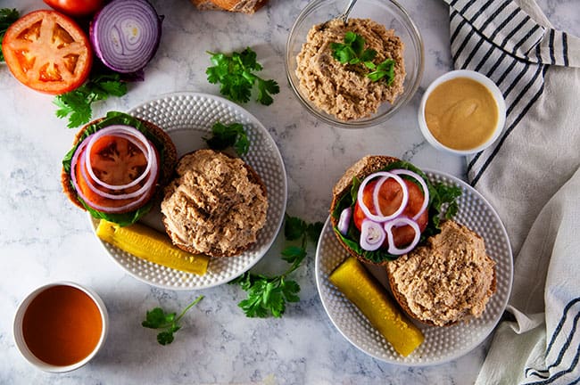 Honey Mustard Chicken Salad sandwich on a white plate with lettuce tomato onion and a pickle