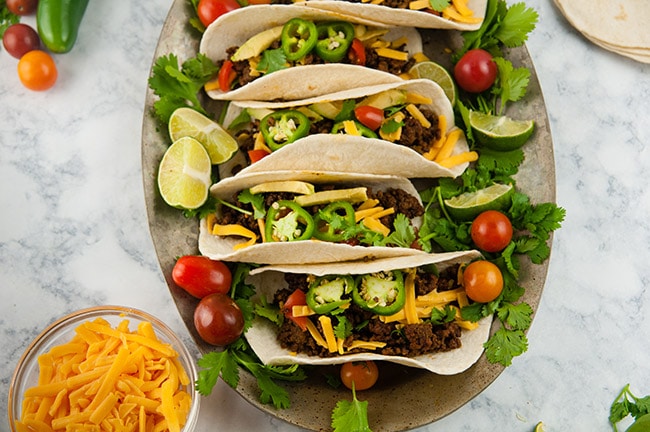 Platter of ground beef tacos on light background