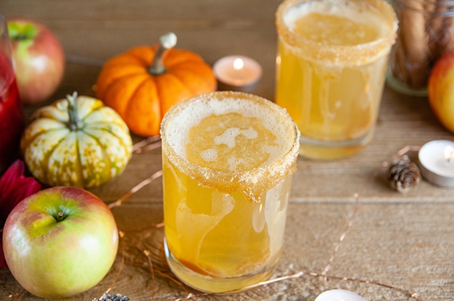 Sparkling Caramel Apple Screwdrivers on wood with pumpkins, apples, and candles