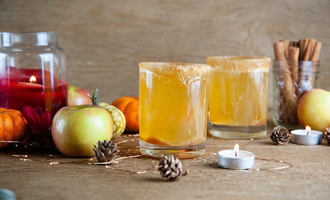 Sparkling Caramel Apple Screwdrivers on wood with pumpkins, apples, and candles