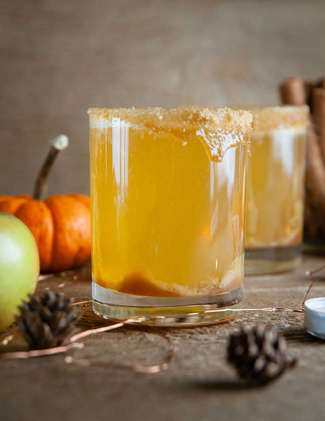 Sparkling Caramel Apple Screwdrivers on wood with pumpkins, apples, and candles