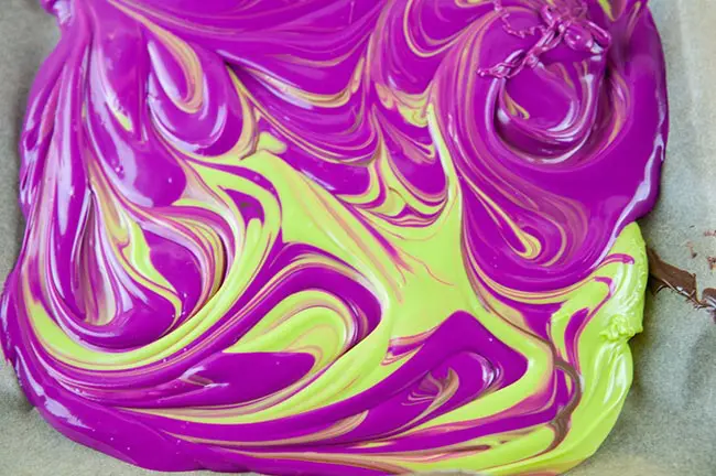 Swirled green and purple candy melted on parchment paper