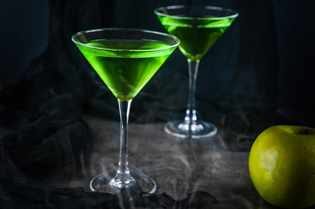 green martinis on black with smoke and a green apple