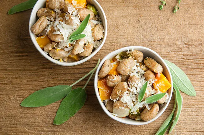 Roasted Sheet Pan Gnocchi in bowls on wood with sage and Fall Vegetables