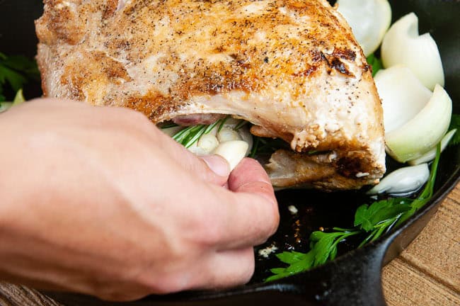 a hand stuffing the garlic cloves into the turkey