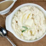 Instant Pot Mashed Potatoes in a white porcelain dish on wood with a gravy boat and spoon