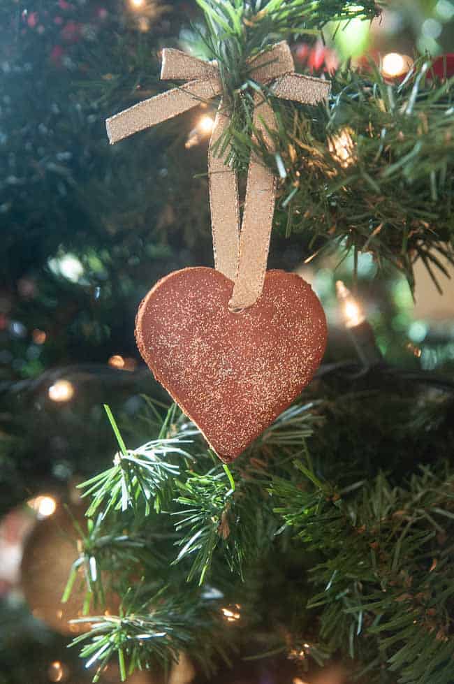 A cinnamon ornament shaped like a heart hanging on a Christmas tree