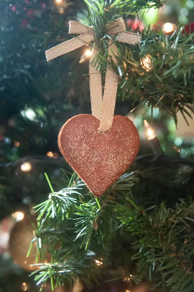 A cinnamon ornament shaped like a heart hanging on a Christmas tree