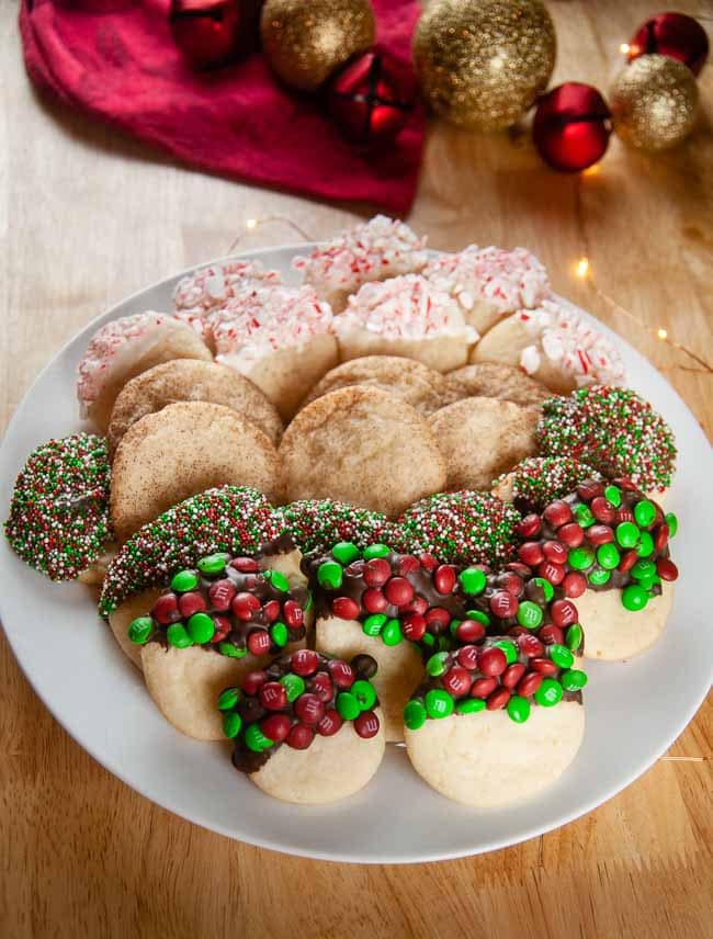 4 kinds of sugar cookies on a white plate on wood