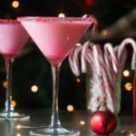 white chocolate candy cane martinis on a dark background in front of a christmas tree