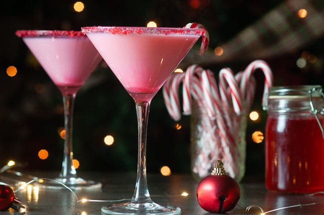 white chocolate candy cane martinis on a dark background in front of a christmas tree