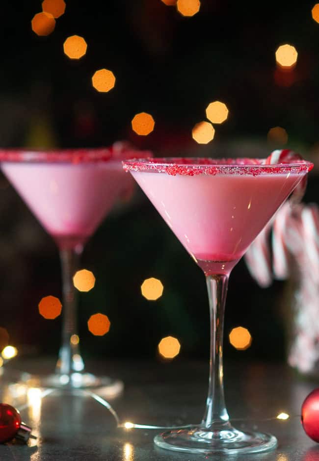 white chocolate candy cane martinis on a dark background in front of a christmas tree