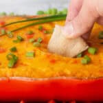 dipping a pita wedge into buffalo cauliflower dip