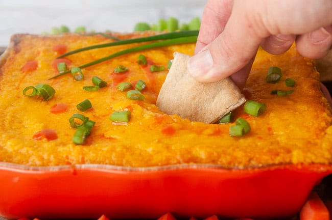 dipping a pita wedge into buffalo cauliflower dip