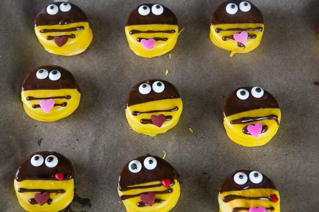 Finish decorating the bumblebee cookies by piping a strip or two across the yellow and attaching a heart sprinkle for the stinger