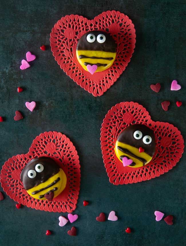 Bumblebee cookies perfect for Valentine's Day on red heart doilies on black