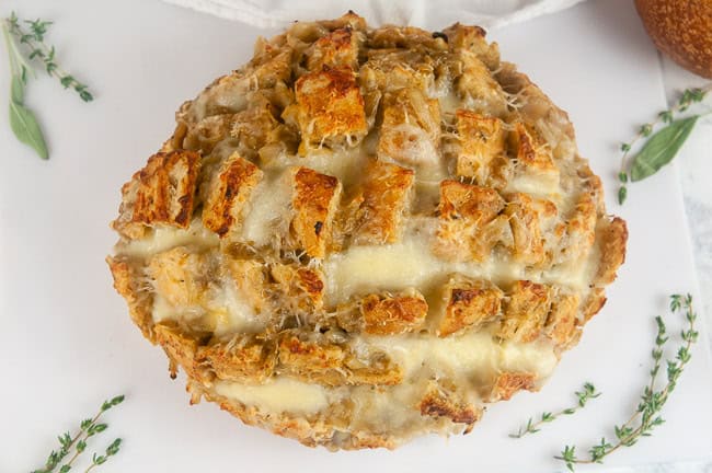 A loaf of pull apart French onion bread on white with herbs