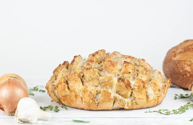 French onion pull apart bread on a cutting board on white