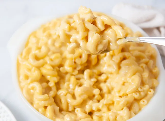 A white bowl full of creamy macaroni and cheese that was made in the pressure cooker.