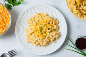 A white bowl and a white plate full of creamy macaroni and cheese that was made in the pressure cooker.