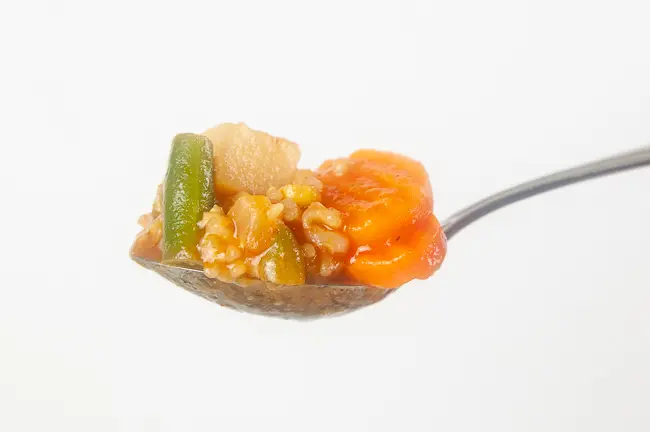 a spoonful of vegetable soup on white