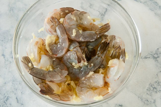 shrimp in a bowl with pressed garlic and lemon