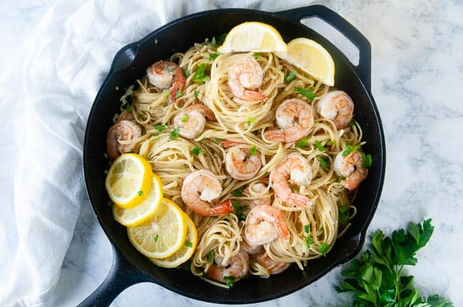A skillet full of shrimp scampi on white
