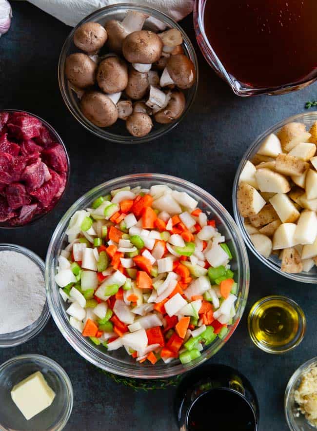 Ingredients for Dutch Oven Beef Stew: Beef, Carrots, Celery, Onions, Garlic, Potatoes, Mushrooms, Butter, Olive Oil, Flour, Thyme, Bay Leaf, Wine, and Stock