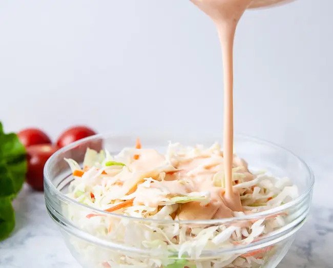 Pour the dressing over the cabbage mix to create sweet and spicy Asian coleslaw