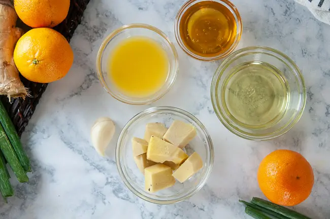 Ingredients for creamy orange ginger dressing: orange juice, honey, peeled ginger, olive oil, garlic, rice wine vinegar, soy sauce