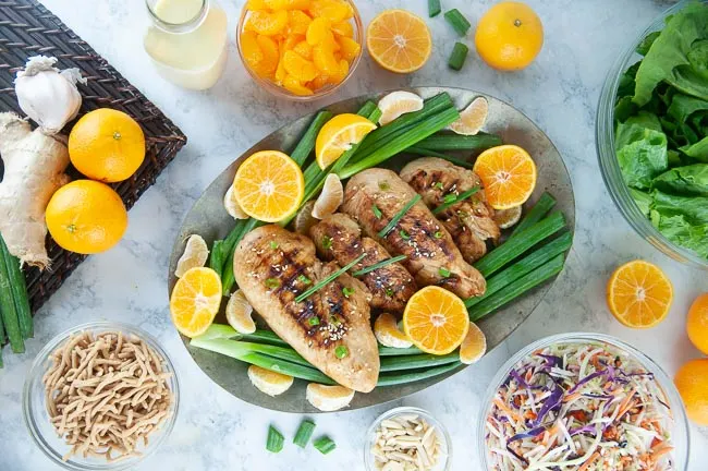 Ingredients for mandarin chicken salad: Grilled chicken breasts, chopped romaine, rainbow slaw, mandarin oranges, slivered almonds, chow mein noodles, and dressing