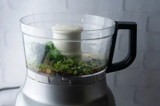 Add the herbs, olive oil, lemon juice and vinegar to a food processor.