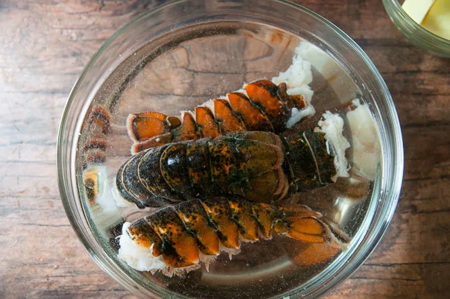 Start by thawing frozen lobster tail in a bowl of water.