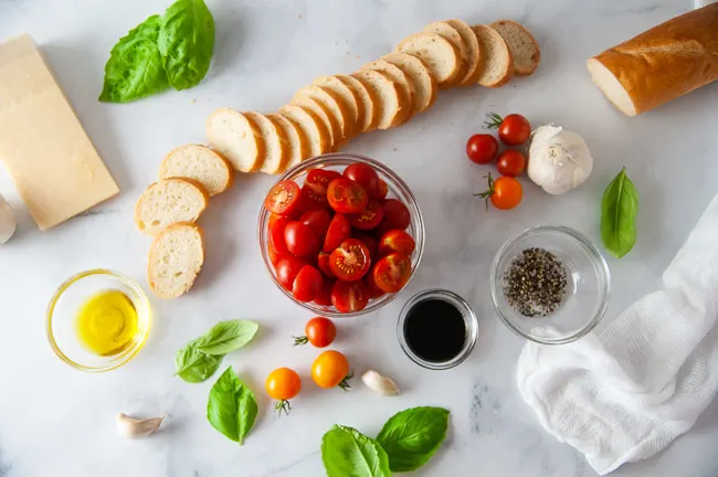 Ingredients for Roasted Tomato Bruschetta: Slices of French Baguette, Olive Oil, Cherry Tomatoes, Garlic, Salt and Pepper, Parmesan Cheese, Basil and Garlic