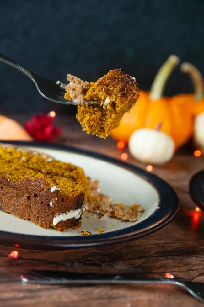 A forkful of this baked good is held above a plate of pumpkin bread just ready to be devoured.