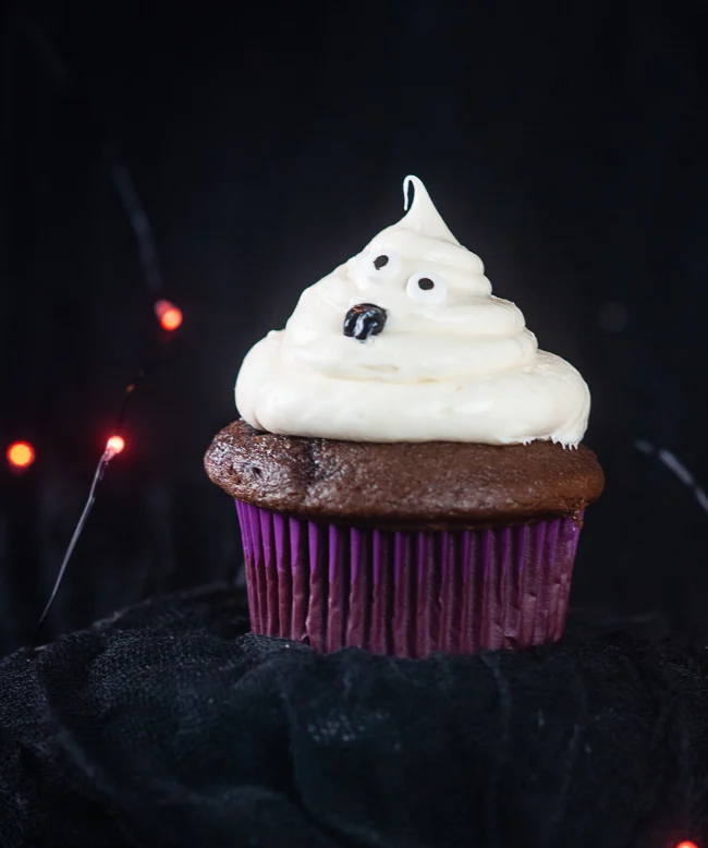 A cute ghost cupcake for Halloween sits on a black background