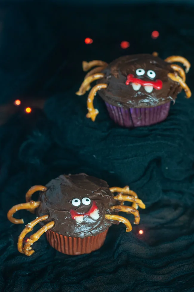 Easy Spider Cupcakes are a fun Halloween treat to make with the kids. Cupcakes decorated like spiders with pretzel legs on black with orange lights.