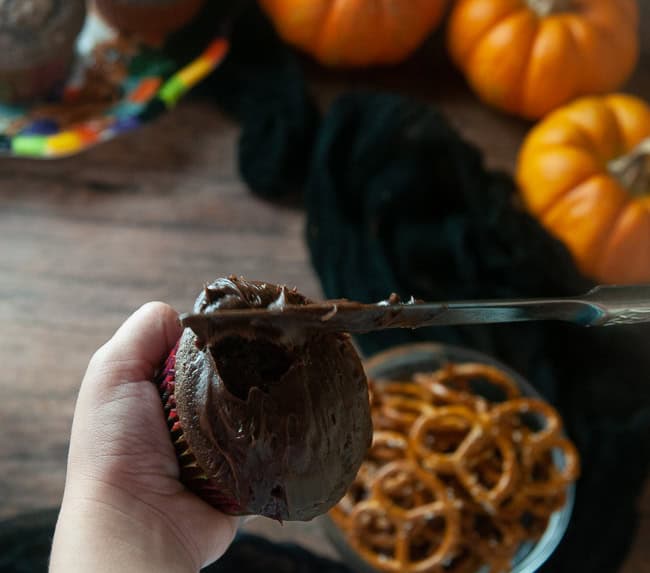 A child using a butterknife to frost a chocolate cupcake