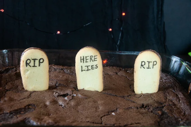 Push the decorated cookies into the brownies so they stand up and form headstones.