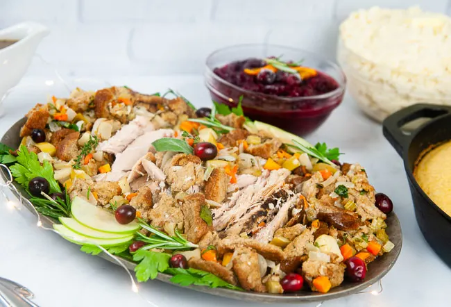 Apple Cider Turkey Breast sliced and spread out on a silver serving platter with stuffing makes a perfect small holiday entree.