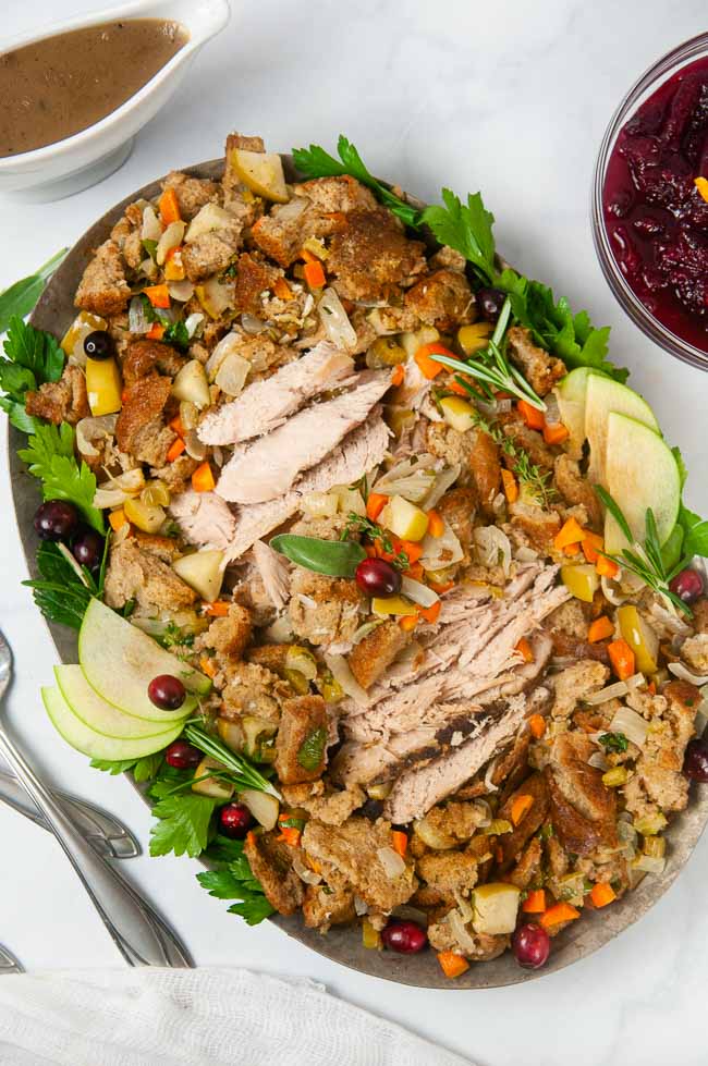 Apple Cider Turkey Breast sliced and spread out on a silver serving platter with stuffing makes a perfect small holiday entree.