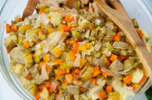 Sauteed carrots, onions, celery and apples in a large bowl getting tossed with bread cubes for stuffing