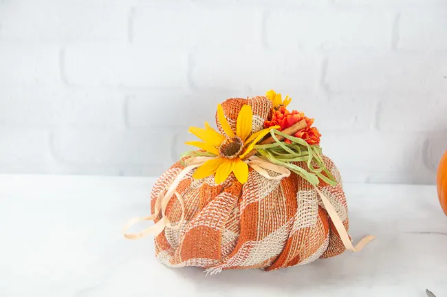 A plaid burlap fabric pumpkin with fall florals and ribbons 